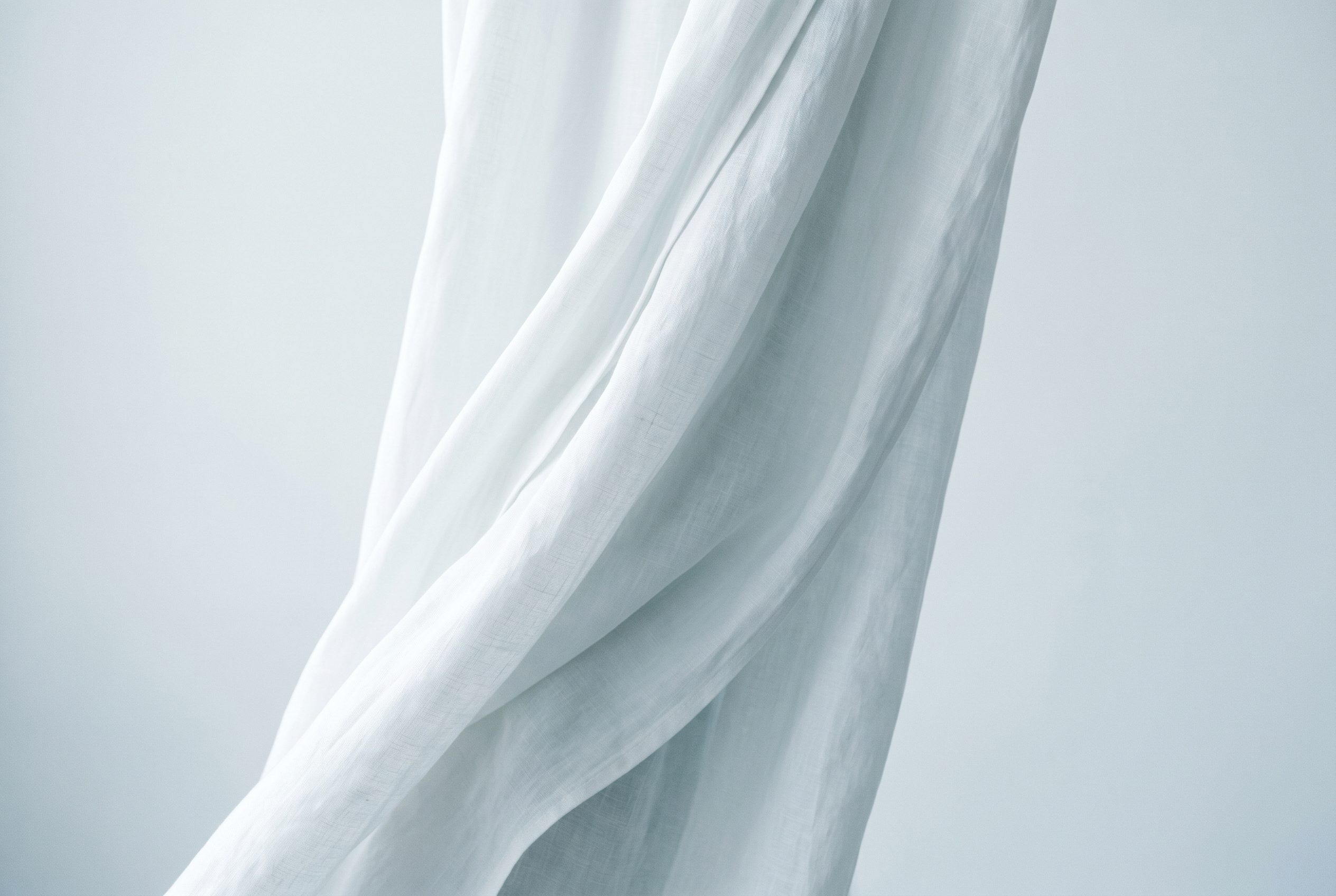 Symbolbild Palliativmedizin: weich fließendes weißes Leinen in kühlem Tageslicht